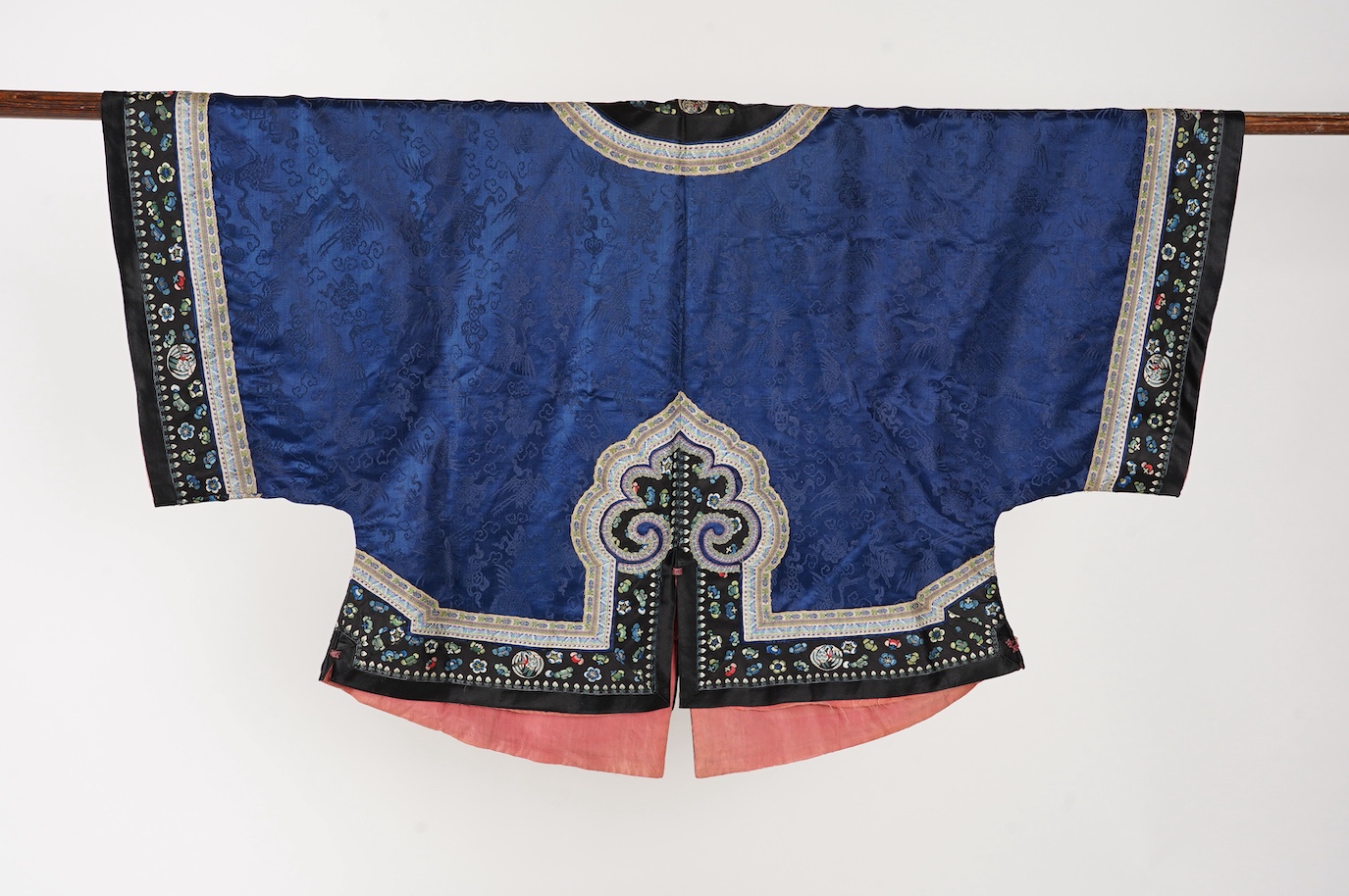 A late 19th century Chinese blue silk damask jacket, woven with Phoenix and auspicious symbols. The jacket edged with ornate rows of braiding and silk embroidery, the interior with original pink silk lining. The jacket f